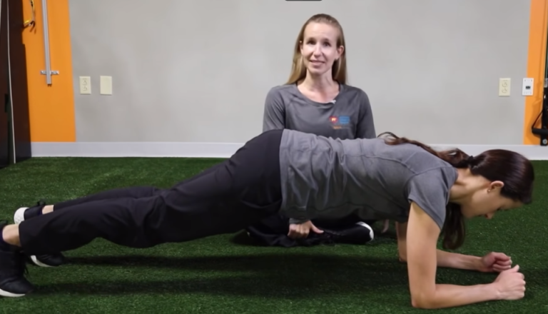 Image of a woman performing a plank with a personal trainer